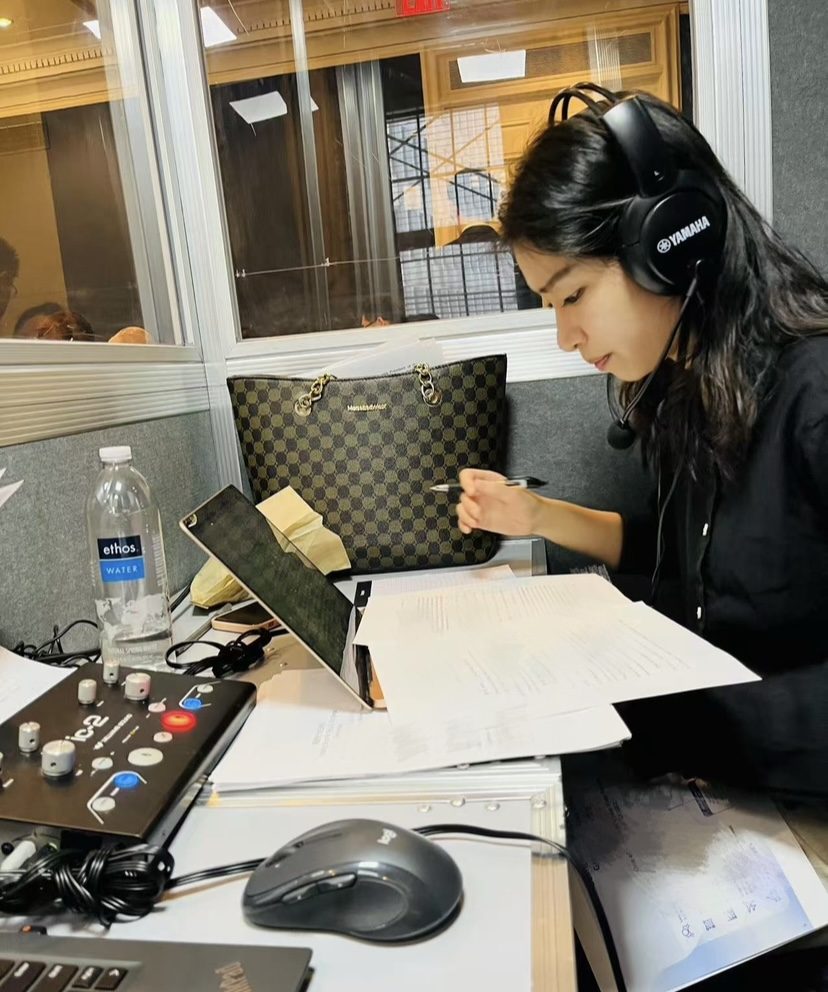 Cheng Shen taking notes with headphones on in the booth